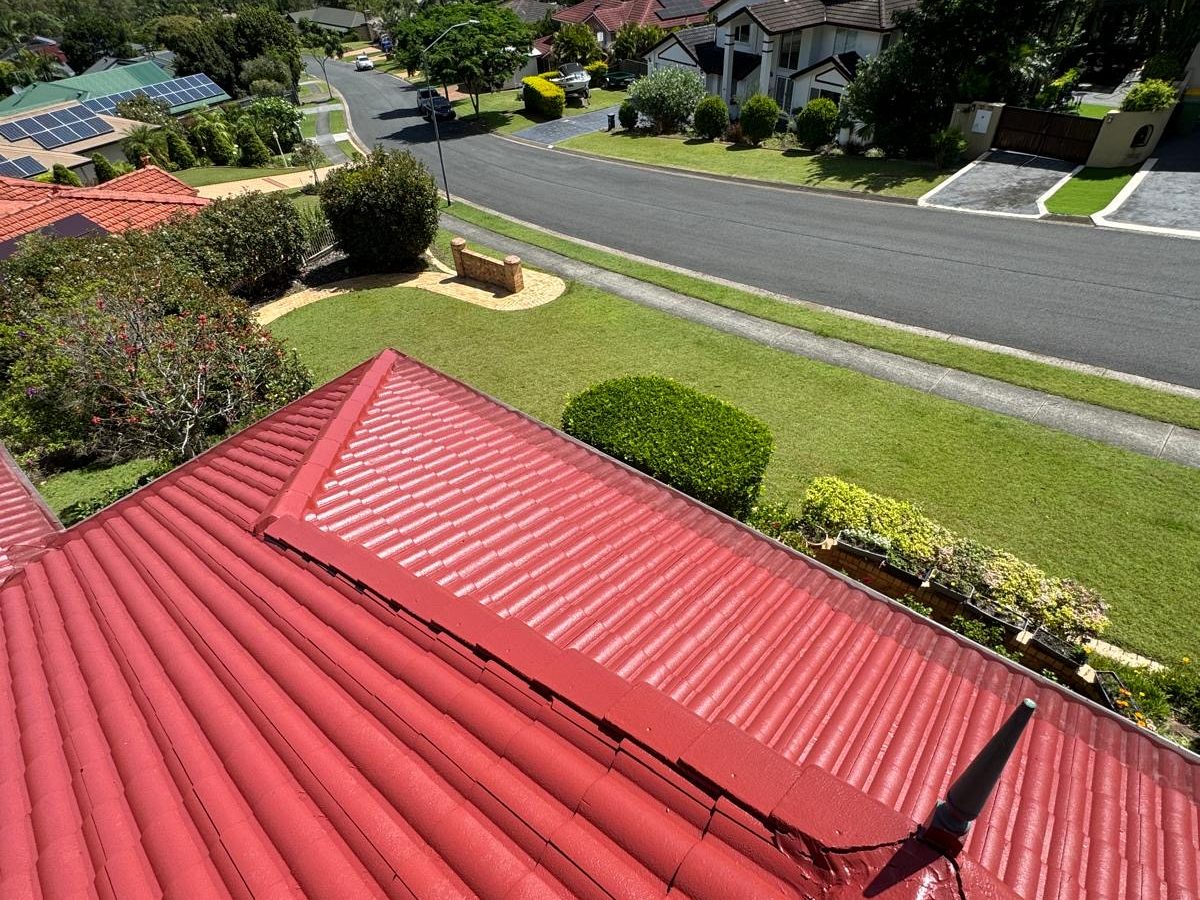 A tile roof restored in a deep gloss red, seen along the ridge
