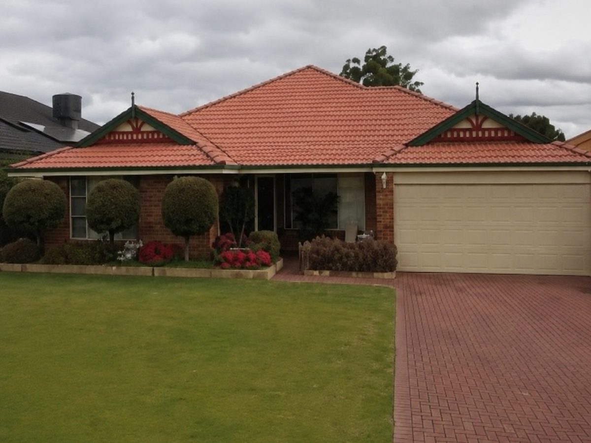 A faded terracotta tile roof on a brick home before restoration